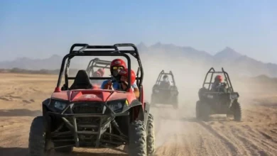 Four individuals riding all-terrain vehicles across a sandy desert landscape under a clear blue sky. Buggy Adventure in Agafay Desert
